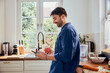 © baranq - Man using mobile phone while having coffee in kitchen