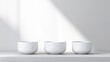 © PACESTOCK - Three identical white bowls sit on a white surface. Soft, natural light illuminates them. The image is clean and minimalist, with a serene mood. Its high-quality, showcasing simple elegance. Perfect
