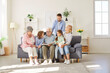 © Studio Romantic - Big family of different generations gathering on sofa around grandfather, looking through photo album. Parents, children and grandparents enjoying leisure time and good memories together at home.