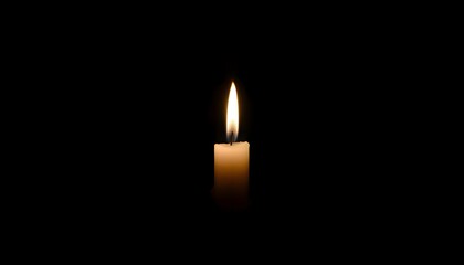 Wall Mural - lit candle in the dark with a black background