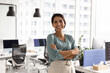 © fizkes - Happy successful female Latin businesswoman posing in office workspace alone, looking at camera, smiling, standing with arms crossed. Confident cheerful business leader woman portrait