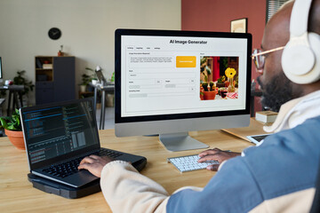 Fototapete - Young African American man typing on keypads of two desktop computers while using or testing new software by workplace
