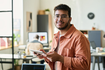 Poster - Young smiling male programmer or software developer looking at camera while working over new project in coworking space