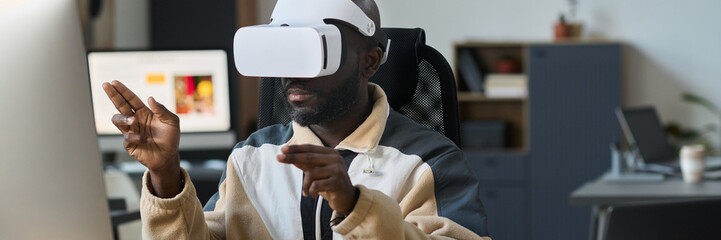 Fototapete - Header of young modern businessman in VR headset sitting in front of desktop computer and preparing virtual presentation