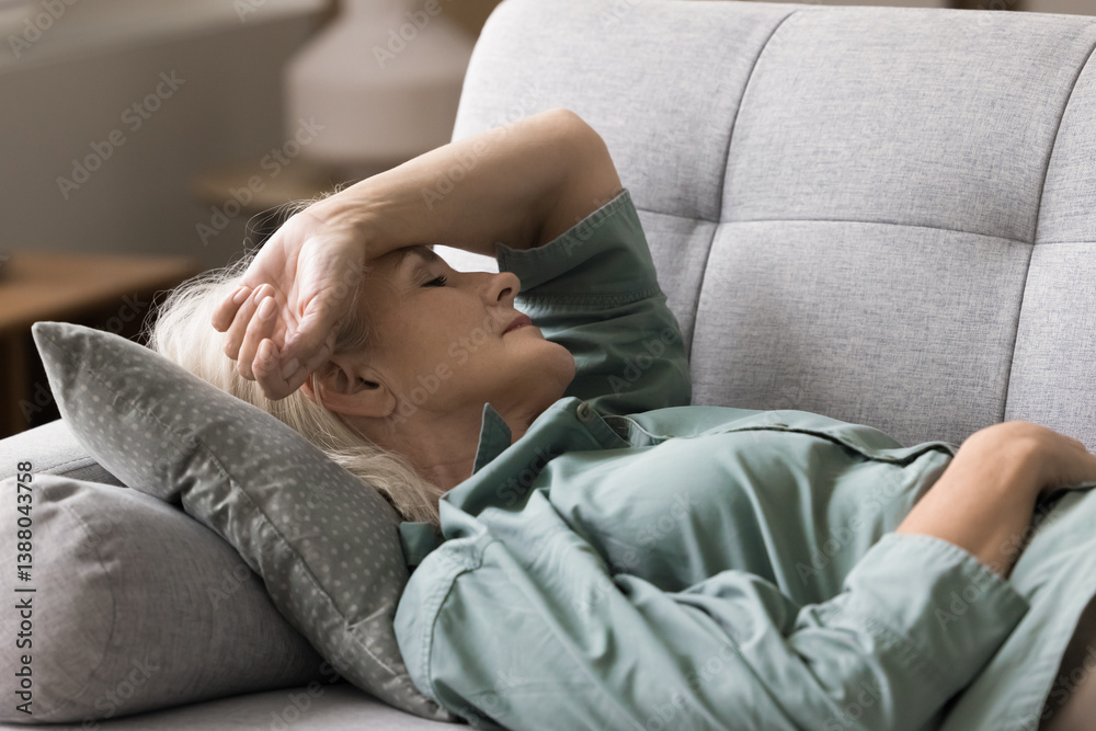 Pause to relax. Portrait elderly woman retiree lying down on sofa with closed eyes hold hand on head take sleep nap to rest feel weak dizzy tired fatigue find moment of relief from menopause symptoms