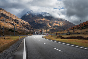 Wall Mural - empty asphalt road winding through alpine mountains in clouds at sunset in autumn. landscape with ma