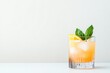 © Сергей Захаров - single glass of vibrant cocktail garnished with slice of citrus and sprig of mint sits against stark white background