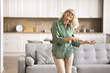 © fizkes - Active and happy retirement. Energetic joyful mature female pensioner dancing jumping with excitement in cozy interior of large modern house feeling healthy free celebrate joy of mortgage loan paid