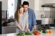 © fizkes - Beautiful couple in love cooking together fresh, natural salad, cutting organic vegetables, hugging, enjoy romantic dating, time together and homemade food preparation stand in modern kitchen at home