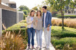 © fizkes - Real estate agent holding tablet, presenting property details, market analysis, contract terms, reviewing listings or pricing, consulting young couple standing outdoors in modern residential complex
