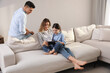 © New Africa - Family with little daughter using tablet on sofa in living room