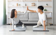 © Prostock-studio - Joyful millennial asian man and woman in sportswear cheering up each other while planking at home, giving high five and smiling, doing exercises on fitness mats at living room, healthy lifestyle