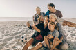 © Marko Geber - Multigenerational family taking a selfie with a smartphone on a sandy beach on their holiday vacation