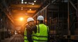 © rdkcho - Two Male Engineers in Hard Hats and Safety Vests Collaborate in an Industrial Factory Setting