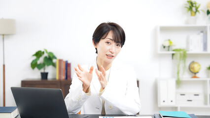 Leinwandbilder - カメラ目線で会話する白衣のミドル女性