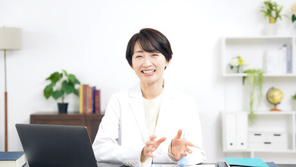 Leinwandbilder - カメラ目線で会話する白衣のミドル女性