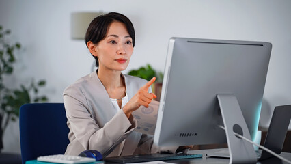 Leinwandbilder - 暗いオフィスでパソコンを使って作業する女性ビジネスパーソン