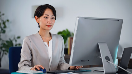 Leinwandbilder - 暗いオフィスでパソコンを使って作業する女性ビジネスパーソン