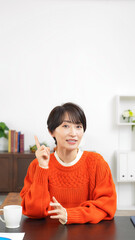Leinwandbilder - 部屋で上を指さしながら話すミドル女性