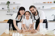 © sofiko14 - Caucasian parents and child cooking together in kitchen, smiling and working with dough. Family bonding, preparing food at home, using rolling pin. Happy atmosphere, teamwork, teaching skills.
