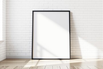 Poster - Blank poster frame leaning against white brick wall in sunlight.