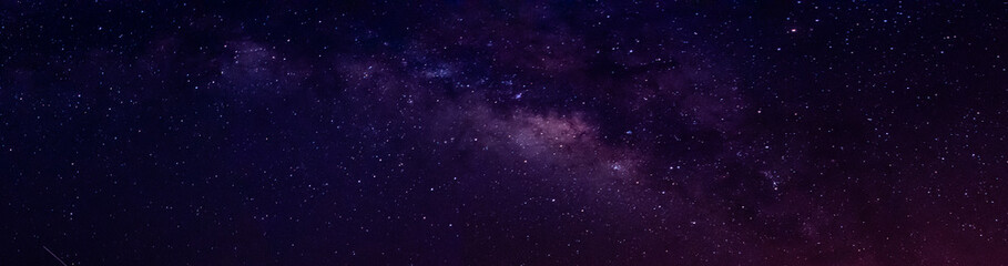 Milky way in night sky and stars on dark background with noise and grain. Long exposure and white balance. Panoramic photo. 