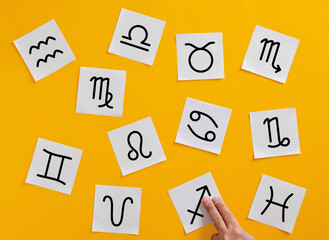 astrologer arranging zodiac signs on yellow background