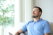 © Antonioguillem - Man at home breathing fresh air on a sofa
