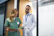 © zinkevych - Female nurse in uniform walking in hospital corridor with male doctor discussing patient treatment