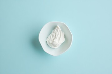 Aufkleber - A small white bowl holds a generous serving of fluffy whipped topping, beautifully contrasting with the soft blue backdrop