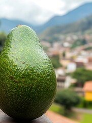 Aufkleber - A perfectly shaped avocado rests against a blurred backdrop of a serene mountain village under a cloudy sky : Generative AI