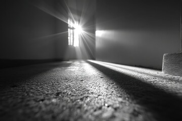Poster - Sunlight piercing through a window, casting strong rays across a grainy floor, creating a stark contrast and dramatic lighting effect in monochrome scenery.