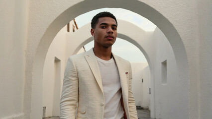 Poster - A person in a white suit stands under an archway, offering a sense of elegance and sophistication