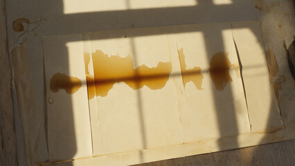 Poster - A brown stain on a piece of paper, likely from a leaky pipe or spill, sits next to an open window