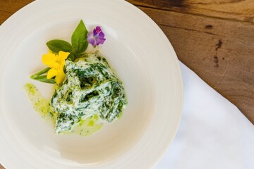Poster - Fresh green dish decorated with edible flowers served on a white plate at a trendy restaurant