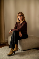 Poster - Smiling mature woman sitting on her living room