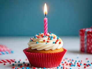 Poster -  A birthday cupcake with white frosting and colorful sprinkles on top of it, sitting on a table with wrapped presents in the background.