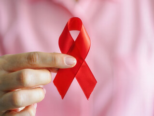 Poster -  A hand holding a red ribbon, symbolizing awareness for breast cancer.