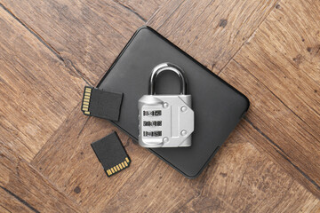 Poster - External hard drive, SD memory cards and combination padlock on wooden table, flat lay