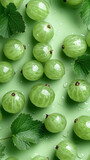 Fresh green gooseberries scattered on a light green surface with leaves and droplets of water highlighting their texture