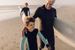© Marko Geber - Multigenerational family of male surfers getting ready to surf on a sandy beach
