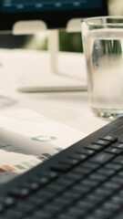 Poster - Vertical video Modern workspace with analytical data paperwork documents in bright office environment with potted plants. Tablet on desk with digital statistics charts displayed on screen, close up