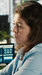 Poster - Vertical video Stressed worker in office sighs, burdened by too many documents to review. Tired employee at work feeling overworked while analyzing business performance metrics, camera A