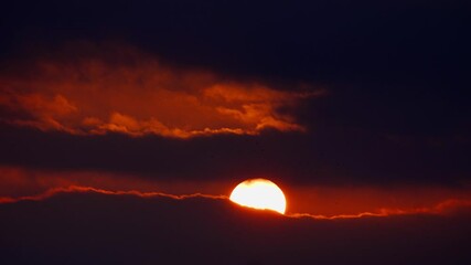Wall Mural - the sun is shining through a black red sunset sky. an impressive cloudscape of dark clouds as abstra