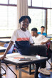 © WavebreakMediaMicro - In school, smiling student sitting on desk with tablet and notebook nearby