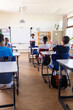 © WavebreakMediaMicro - Indian female teacher leading classroom discussion with students sitting at desks in school