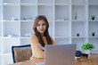 © Jirapong - Smiling young woman engaged in online e-learning at her desk with a laptop notebook and headphones creating a positive study atmosphere for success