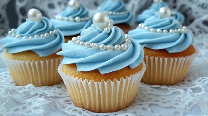 Poster - Beautifully decorated cupcakes with soft blue frosting and delicate edible pearls, placed on vintage lace, creating a refined and celebratory atmosphere.