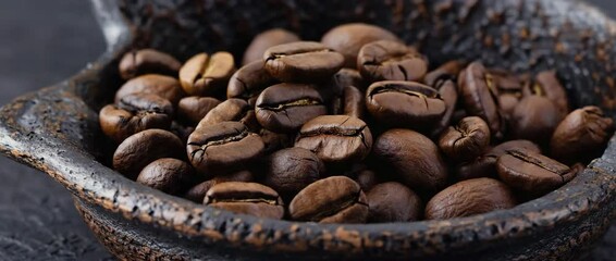 Poster - Cinematic close-up video of roasted coffee beans gently shifting inside a dark bowl, 