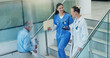 © WestLey/peopleimages.com - People, stairs and doctors in hospital, conversation and smile with advice, feedback or talking. Medical, women or professional in clinic, discussion or communication with mentor, steps or healthcare
